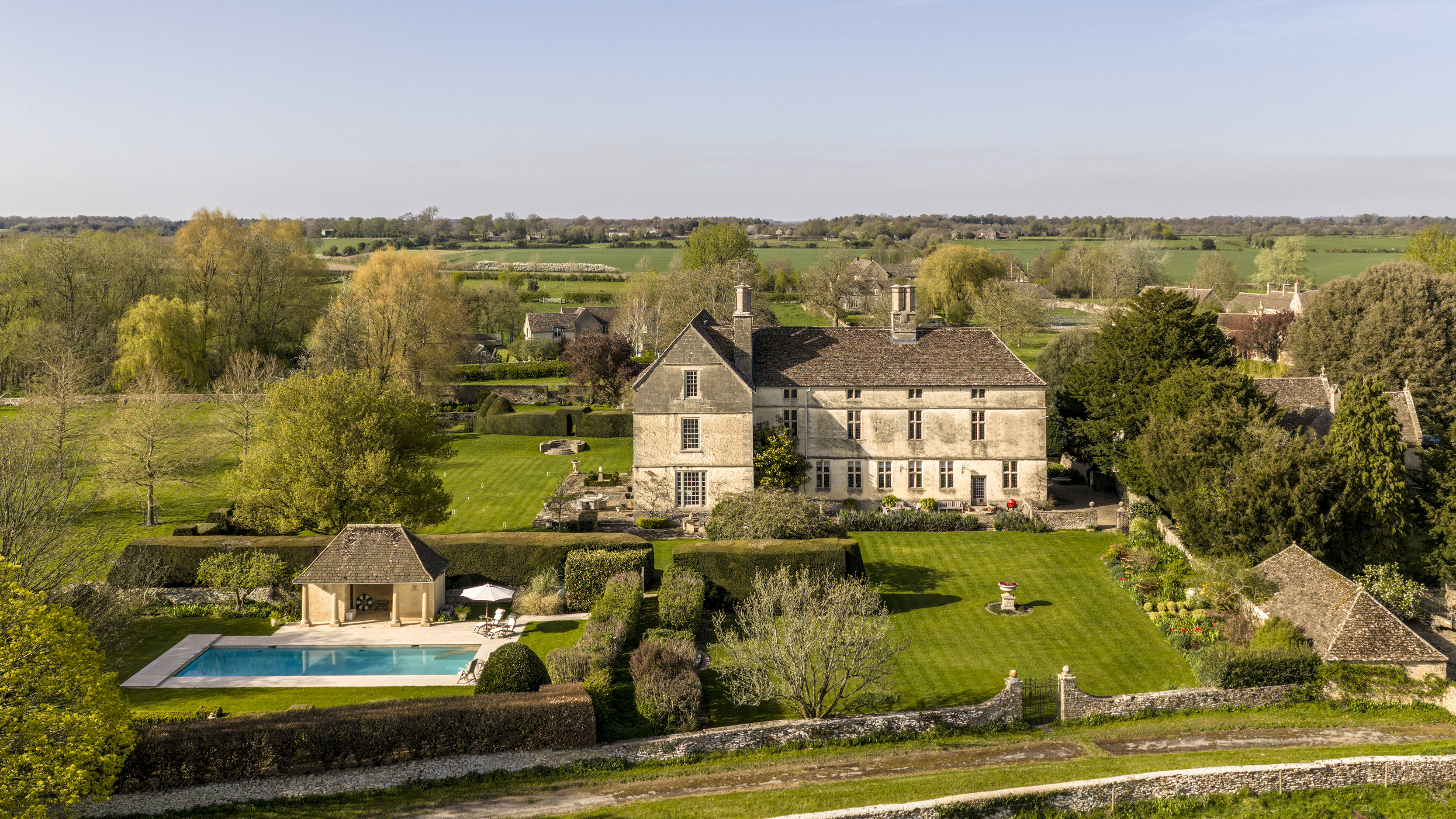 Aerial view of a grand Cotswolds manor house and estate